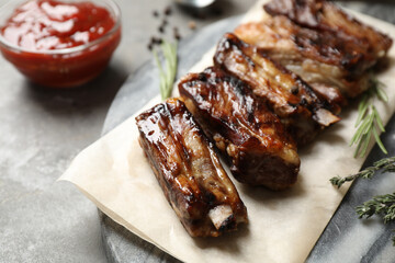 Delicious grilled ribs served on grey table, closeup