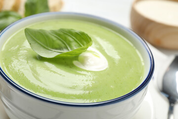 Tasty homemade zucchini cream soup in bowl, closeup
