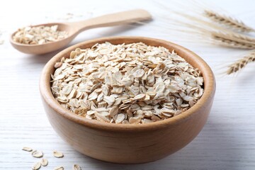 Oatmeal, bowl and spoon on white wooden table