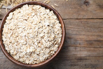 Bowl with oatmeal on wooden table, flat lay. Space for text