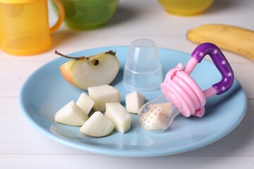 Fototapeta na wymiar Nibbler with fresh apple on white wooden table. baby feeder