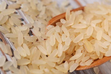 Rice groats scattered on a light wooden background closeup. Shallow depth of field