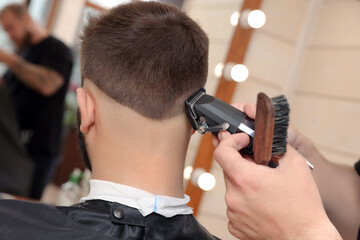 Naklejka premium Professional hairdresser working with client in barbershop, closeup