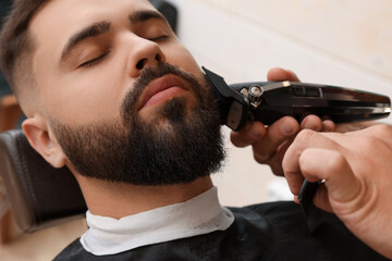 Professional hairdresser working with client in barbershop, closeup