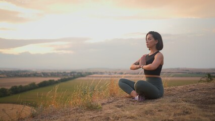 Calm serene sporty young woman meditate while sitting in namaste pose with eyes closed
