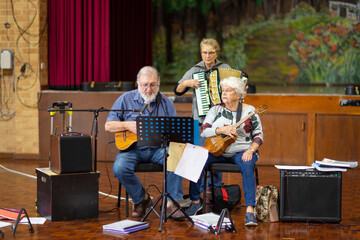 three seniors rehearsing musical piece in a hall