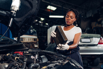Obraz na płótnie Canvas Woman auto mechanic checking air filter and repair maintenance auto engine is problems at car repair shop.