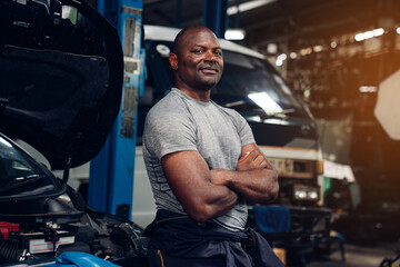 Portrait of man auto mechanic working at car repair shop with looking at camera.