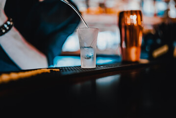 bartender pouring alcohol into a shot glass in bar