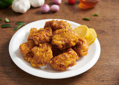 A white plate with fresh, crispy golden fried chicken. Korean style with lemon saurce. Selective focus.