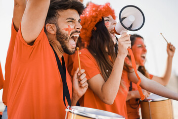 Orange sport fans screaming while supporting their team out of the stadium - Focus on man face