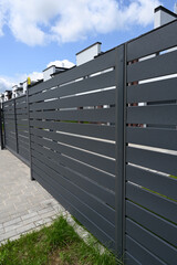 Modern gray metal fence for fencing the yard area. Horizontal metal sections of the fence. Close up