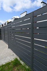 Modern gray metal fence for fencing the yard area. Horizontal metal sections of the fence. Close up