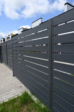 Modern gray metal fence for fencing the yard area. Horizontal metal sections of the fence. Close up