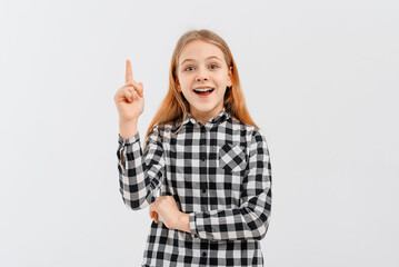 Portrait of smiling teen girl, pointing finger up, showing one, demonstrating banner, standing over white background in casual shirt