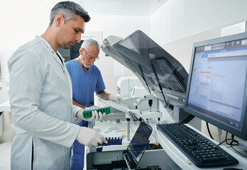 Laboratory technicians analyze blood samples near biochemical automatic blood analyzer in modern...