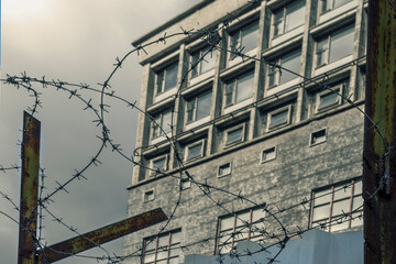 Obraz premium Selective focus. Fence with barbed wire against the background of an old dirty building