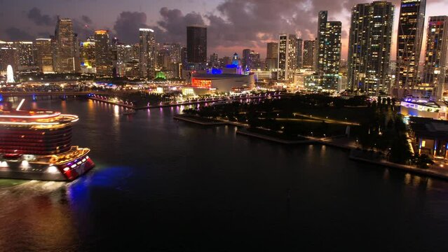 Aerial Time Lapse Shot Of Illuminated Modern Buildings In City, Drone Flying Backwards Over Sea At Night -  Miami, Florida