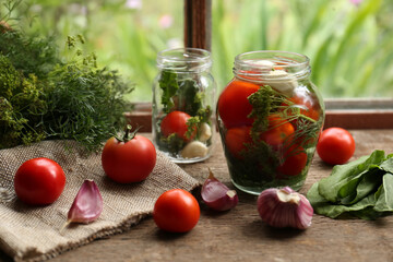 Glass jars, fresh vegetables and herbs on wooden table indoors. Pickling recipe