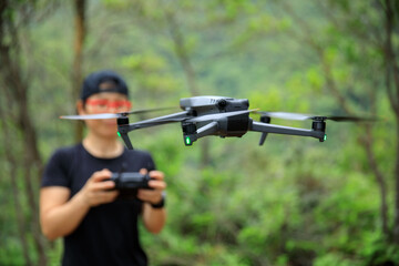 Fototapeta People remote control a flying drone in summer forest obraz