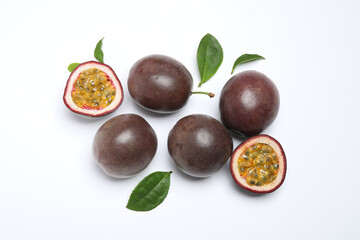 Fresh ripe passion fruits (maracuyas) with leaves on white background, flat lay