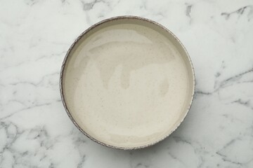 Beige bowl with water on white marble table, top view © New Africa