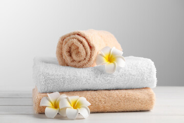 Obraz na płótnie Canvas Soft folded towels and plumeria flowers on white wooden table