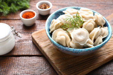 Delicious dumplings with dill on wooden table, closeup