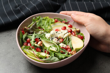 Woman with tasty pear salad at grey table, closeup
