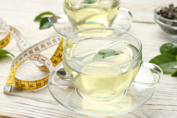 Diet herbal tea with green leaf and measuring tape on white wooden table