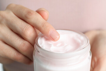 Woman holding jar of hand cream, closeup