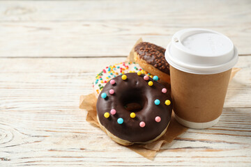 Delicious glazed donuts and coffee on white wooden table