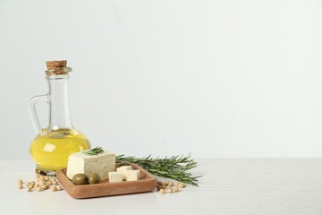 Pieces of delicious tofu with rosemary, olives and soy on white table, space for text
