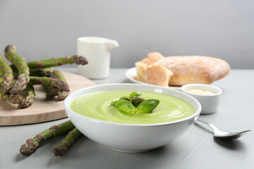Delicious asparagus soup served on grey table