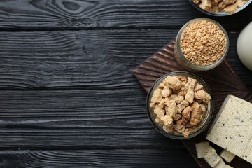 Different natural soy products on black wooden table, flat lay. Space for text