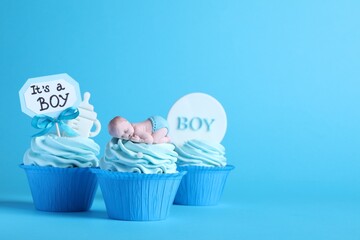 Beautifully decorated baby shower cupcakes with cream and boy toppers on light blue background. Space for text