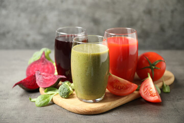 Delicious vegetable juices and fresh ingredients on grey table