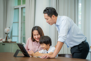 Fototapeta premium Little boy taking online class with parents helping him at home,Boy is writing in his book.