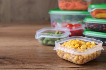 Set of plastic containers with fresh food on wooden  table, space for text
