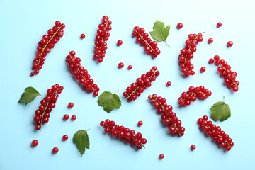 Delicious red currants and leaves on light blue background, flat lay