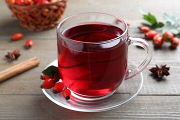 Aromatic rose hip tea and fresh berries on wooden table, closeup