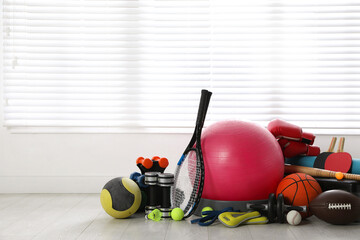 Set of different sports equipment on white floor indoors, space for text