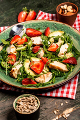 Chicken salad with arugula avocado and strawberries. Plate with a keto diet food. Top view