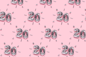 Repetitive pattern made of number 20 silver air balloons with ribbons confetti on a pink...