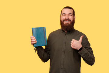 A photo of a man holding a planner and showing a thumb up