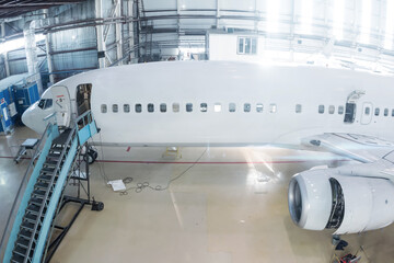 White passenger jetliner in the hangar. Airliner under maintenance. Checking mechanical systems for flight operations