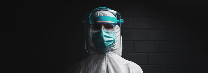 Fototapeta Studio portrait of a doctor in protective suit on black background. Panoramic banner view. obraz