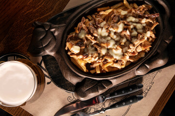 Fried potatoes with mushrooms, sauce and cheese in a large saucepan