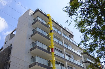 Pipe for debris, waste tube. Suspended sections of yellow garbage chute on a facade of building...