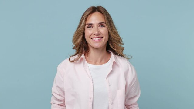 Young smiling charming good kind surprised happy woman wear pink shirt white t-shirt put hands on chest send blow air kiss isolated on plain pastel light blue cyan background. People lifestyle concept